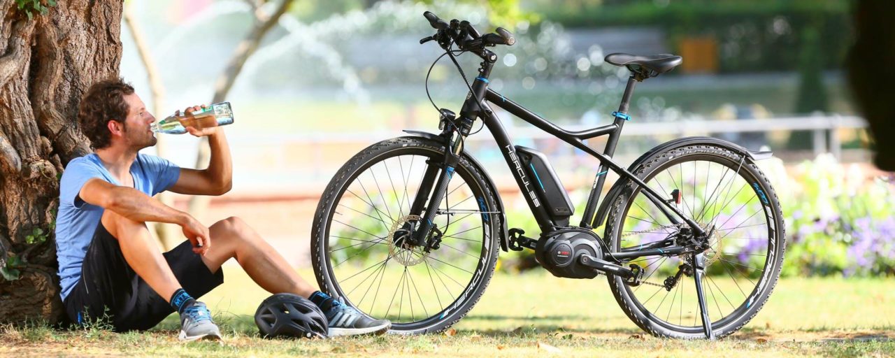 E-Bike kaufen Erlangen, Fürth, Nürnberg Mann sitzt mit seinem E-Bike vor einem Baum und trinkt aus seiner Flsche