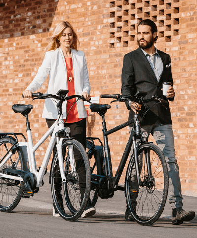 Ein Mann und eine Frau schieben Ihr Elektrorad und unterhalten sich übers Fahrradleasing