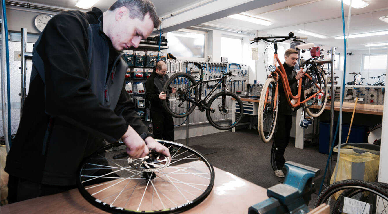 drei Fahrradmechaniker in der Werkstatt reparieren Fahrräder