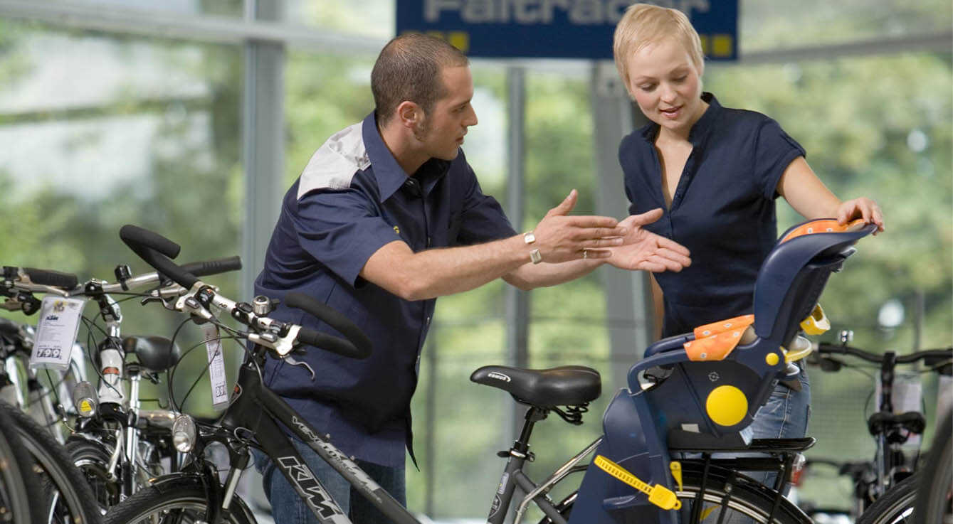 Fahrrad Verkäufer zeigt einer Frau das Fahrrad und berät sie.