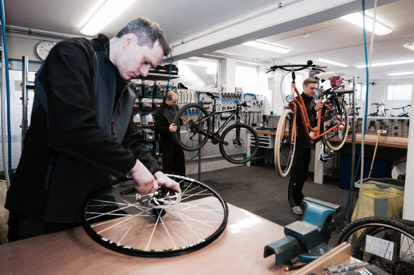 Drei Fahrradmechaniker in der Werkstatt, die reparieren