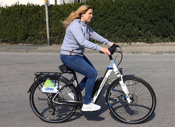 Frau fährt mit einem Pegasus E Bike die Strasse entlang