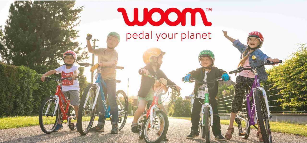 5 Kinder auf Woombikes stehen auf einem Weg und jubeln