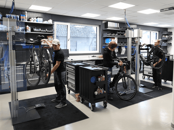 Werkstattmitarbeiter bei der Inspektion und Reperatur mehrer Fahrräder und EBikes in der neuen großen Werkstatt