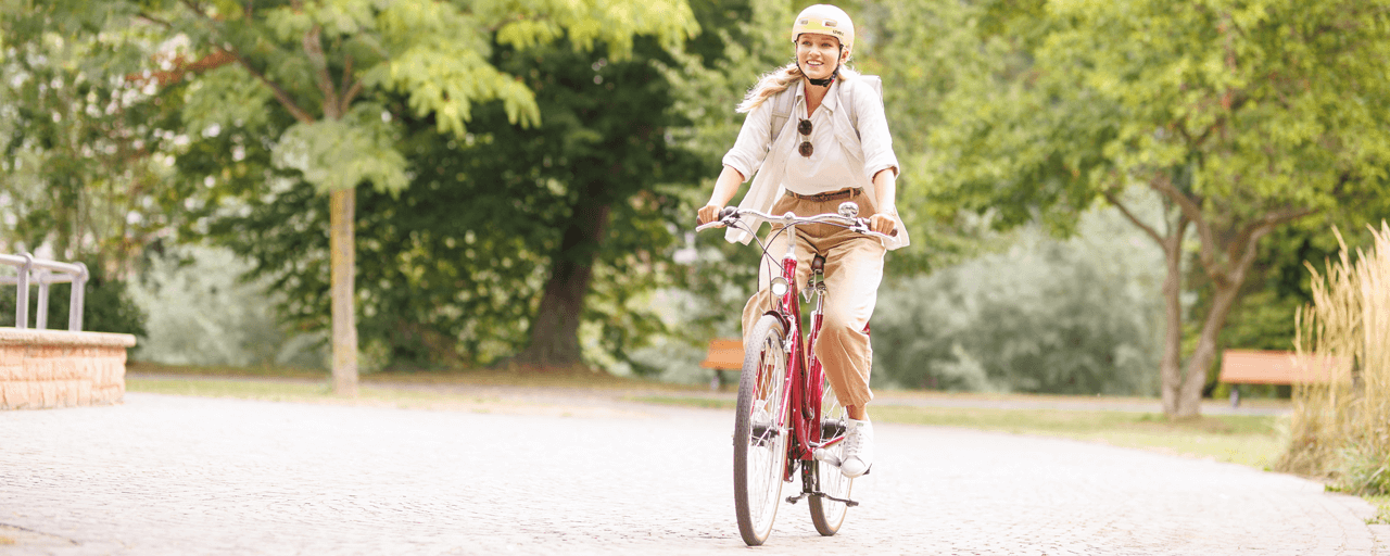 Junge Frau aif einem Roten Damenrad fährt durch den Park