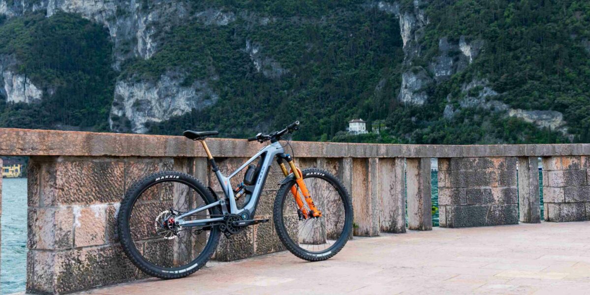 Pinion E-Bikes EIn Bulls Vuca E-Bike mit Pinion Antrieb steht auf einer Brücke mit Bergen im Hintergrund