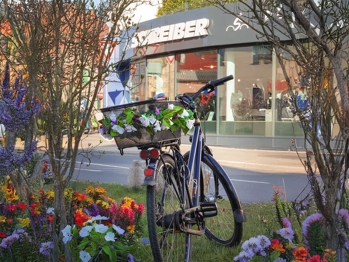Fahrrad fit für die Saison – Bike Center Schreiber hilft! Ein Blumengeschmücktes Fahrrad steht vor dem Bike Center Schreiber